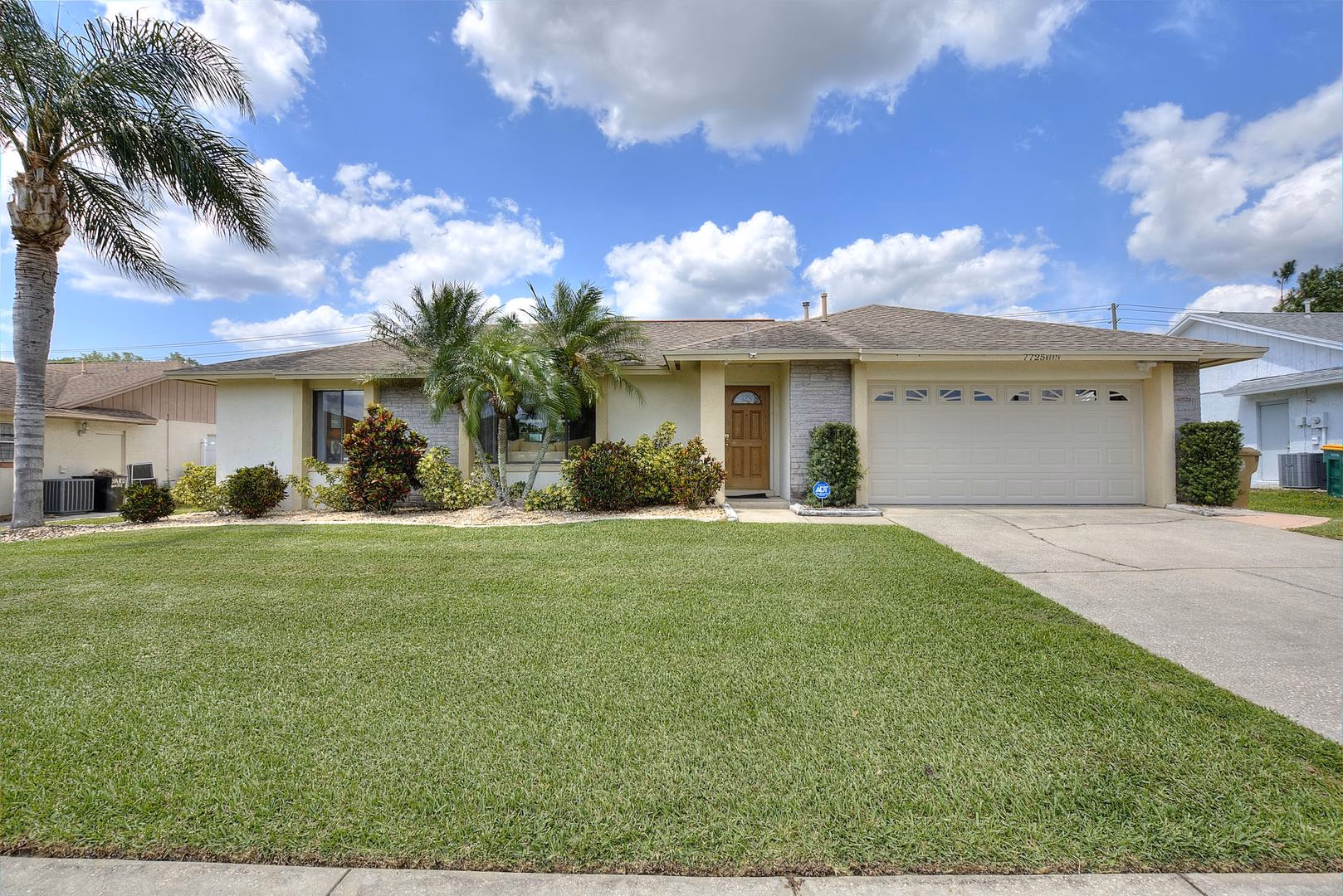 Front of the villa with lawn and palms